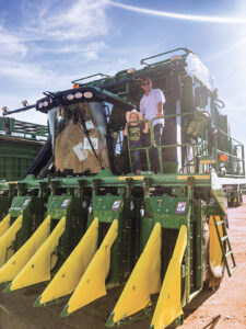 Brian Rhodes and son ride in picker